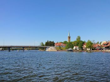 Scenic view of river by building against clear blue sky