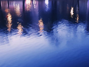 Reflection of illuminated water in lake against sky