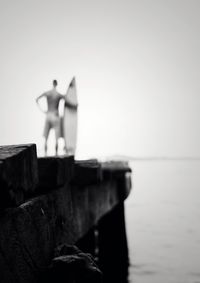 Men standing by sea against clear sky