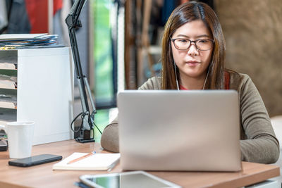 Young woman using phone while sitting on table