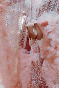 Fashion model dressed in a fluffy pink haute couture boudoir dress, holding beige high heels shoes