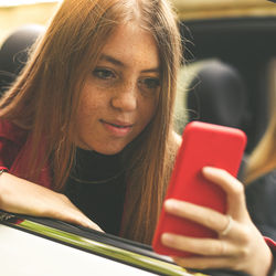 Girl sitting in a car use smartphone. smiling teen chat with friend. young woman enjoying free time