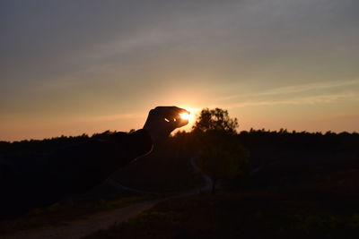 Silhouette person against orange sky during sunset