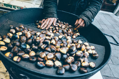 Midsection of person selling roasted chestnut at street