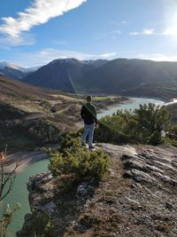 Rear view of man standing on mountain against sky