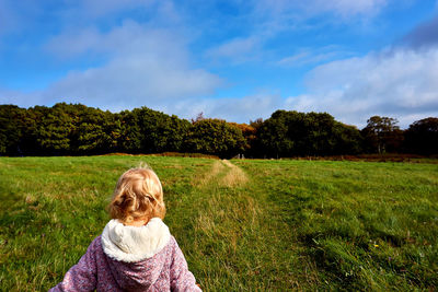 Rear view of woman on grassy field against sky