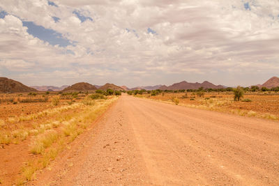 Dirt road along landscape against sky