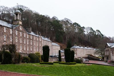 Built structure by trees and buildings against clear sky