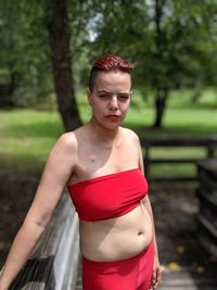 Portrait of young woman standing by railing