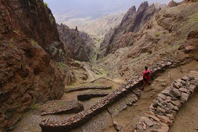 Rear view of woman walking on rocks against mountains