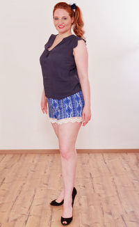 Full length portrait of young woman standing against white wall