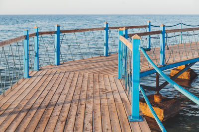 Wooden pier with blue railings. coastal pontoon over red sea waves. sunset light. vacation.