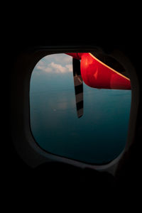 Cropped image of airplane against sky seen through window