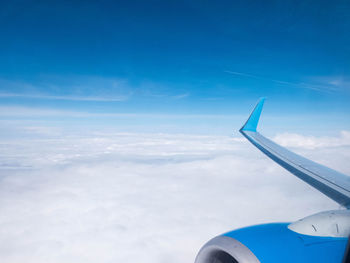 Airplane flying over cloudscape against blue sky