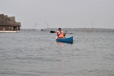 Man boating on lake against sky