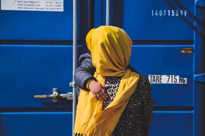 Rear view of woman standing against blue wall