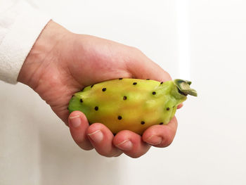 Close-up of hand holding fruit against white background