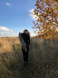 Rear view of woman standing on field against sky