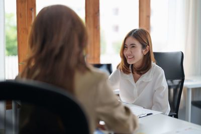 Smiling colleague talking to businesswoman at office