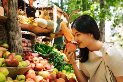 Side view of young woman holding fruit