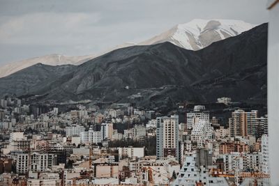 High angle view of buildings by alborz mountain against sky