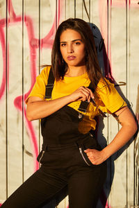 Portrait of beautiful young woman standing against wall