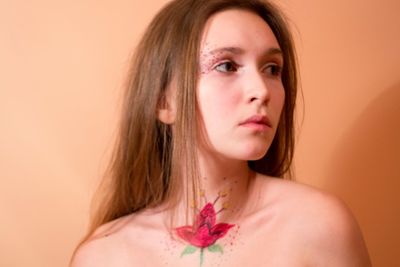 Close-up of woman against orange wall