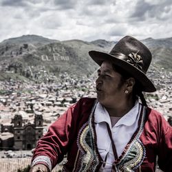 Portrait of man wearing hat against mountains in city