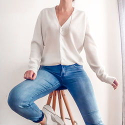 Midsection of young woman standing against wall