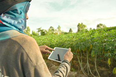 Midsection of man using mobile phone on field