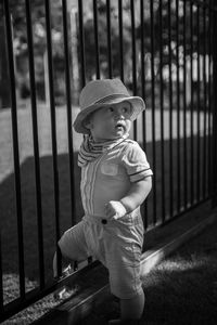 Baby boy standing by fence on playground