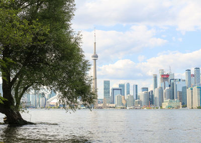 Modern cityscape by river against sky