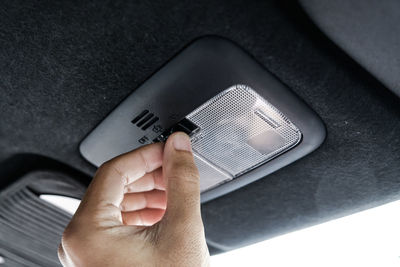 Close-up of hand pressing push button in car