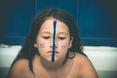 Close-up of sad girl with face paint in bathroom