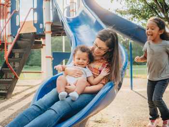 Happy friends sitting on slide at playground