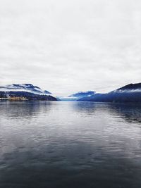 Scenic view of lake by snowcapped mountains against sky