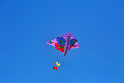 Low angle view of kites against clear blue sky