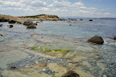 Scenic view of rocks on beach against sky