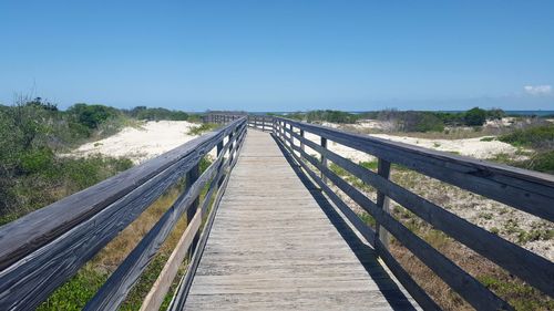 Footbridge over road against clear blue sky