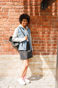 Portrait of smiling girl standing against brick wall