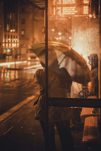 Reflection of man in glass building at night