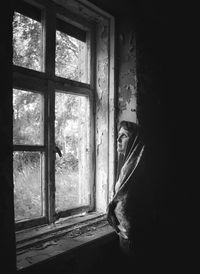 Portrait of man looking through window at home