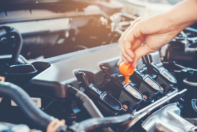 Cropped hands of mechanic repairing car in garage