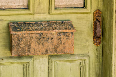 Green wooden door with mottled rusted mailbox