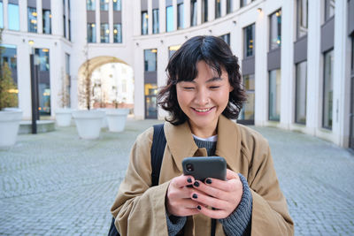 Young woman using mobile phone in city