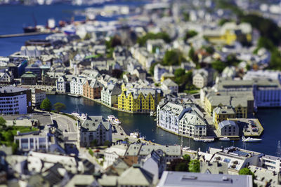 Tilt-shift image of river amidst buildings in city