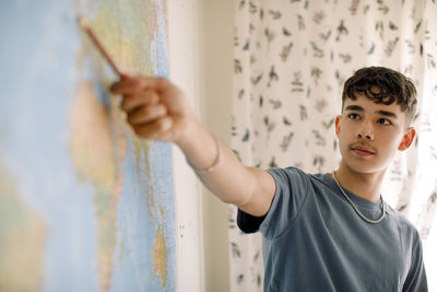 Teenage boy explaining over world map in classroom