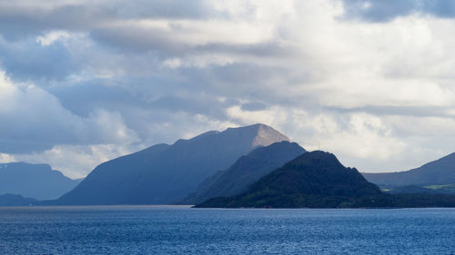 Scenic view of sea by mountains against sky