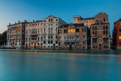 Buildings at waterfront against blue sky