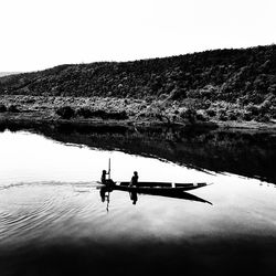 People in boat on lake against clear sky